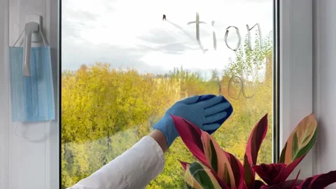 Doctor’s hand cleaning word Isolation period from window. Video stock 163047913