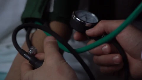 Doctors hand pumping air with ball to measure patients blood pressure Stock Footage 125810148