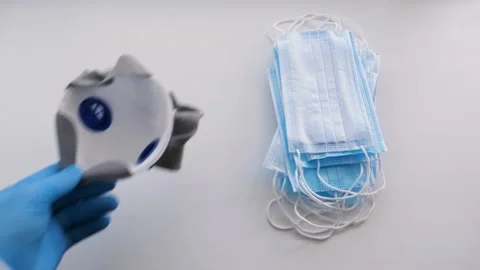Doctor's hand puts a respirator on a table next to medical masks Stock Footage 130439115