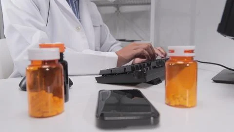Doctor's hand typing computer keyboard and chat message from mobile phone. Stock Photos