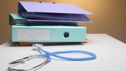 Doctor's hand in a white coat reaching for a stack of colorful ring binders and Stock Footage 324762589