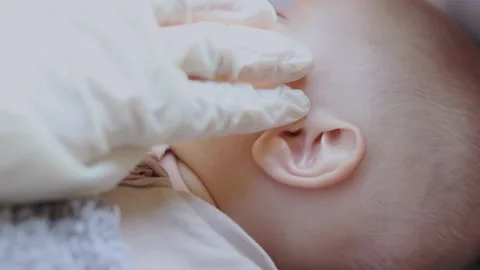 Doctors hand in white glove examines checks baby infant ear 動画素材 158296325