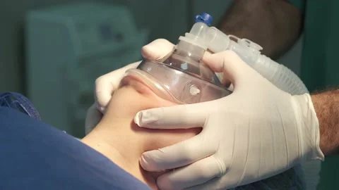 Doctor's hands are holding anesthesia mask on the patient's face Stock Footage 166945316