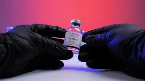 Doctor's hands in black gloves holding vial with coronavirus vaccine Stock Footage 129706857