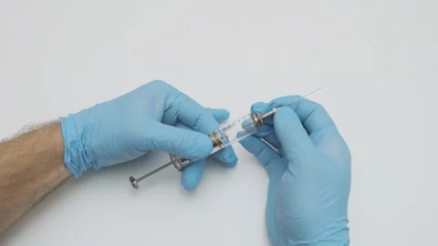 Doctor's hands in blue gloves put metal needle on old glass syringe Stock-Footage 265880442