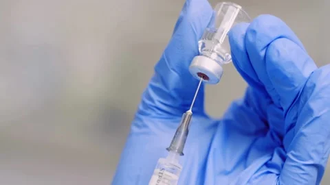 Doctor's hands close-up with Flu Shot Vaccine Vial Dose Hypodermic. Female Stock-Footage 336586945