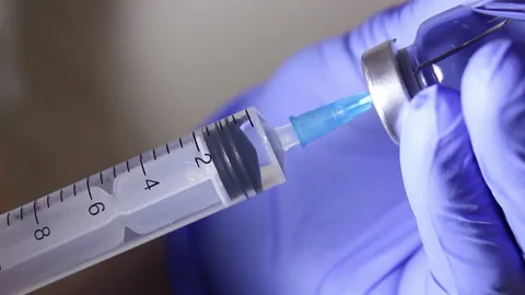 Doctor's hands fill the syringe with vaccine, preparing for the injection of the Stock Footage