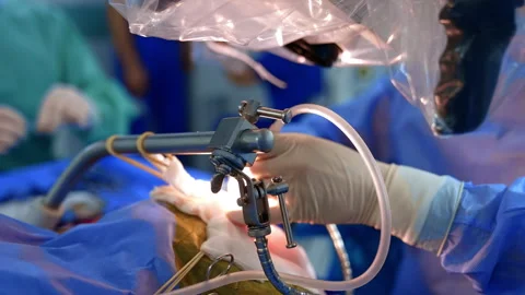 Doctor's hands hold the modern surgical tools. Microscope covered with plastic Stock Footage 334877092