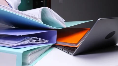 Doctor's hands managing an overwhelming stack of medical binders and patient Stock Footage 324763362