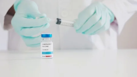 Doctor's hands removing the Covid-19 vaccine from a vial with a syringe Stock Footage