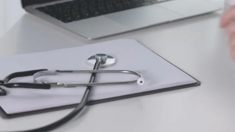 Doctor's hands taking stethoscope from white table in hospital clinic office Stock Footage 206185341