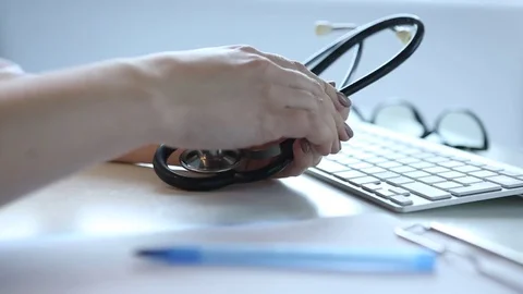 The doctor's hands. Talk with the patient. Stethoscope, keyboard, glasses on the Stock Footage 82659934