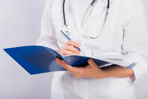 Doctor's hands in a white coat hold a folder and fill out a medical document Stock Photos