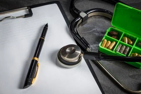 Doctor's kit: stethoscope, container with pills and pen with papers Stock Photos