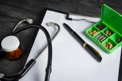 Doctor's kit: stethoscope, container with pills and pen with papers Stock Photos