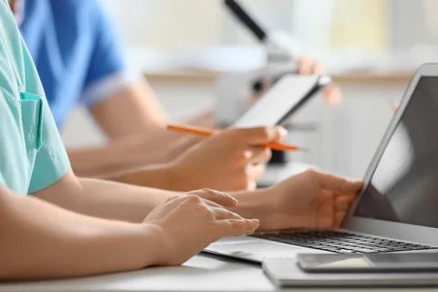 Doctors with laptop and microscope working at table in clinic, closeup Photos