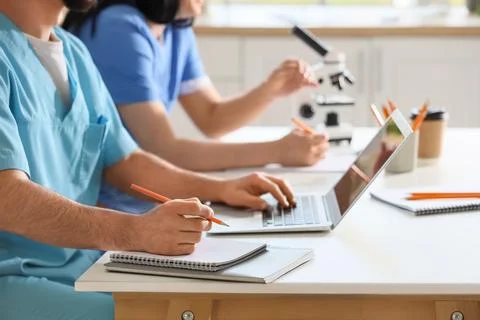 Doctors with laptop and microscope working at table in clinic, closeup Stock Photos
