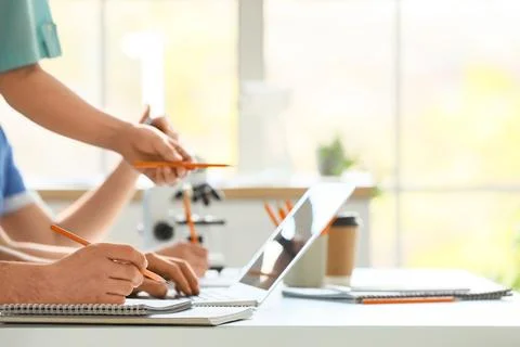 Doctors with laptop and microscope working at table in clinic, closeup Stock Photos