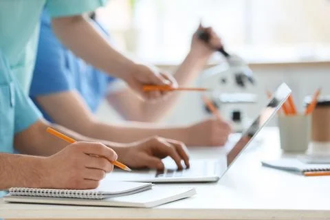 Doctors with laptop and microscope working at table in clinic, closeup Stock Photos