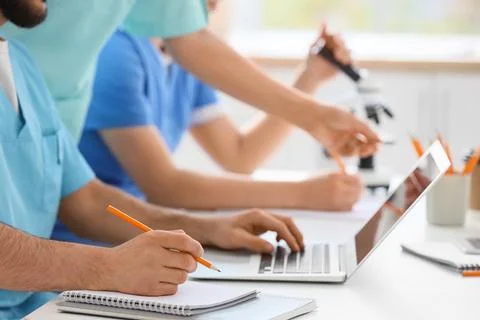 Doctors with laptop and microscope working at table in clinic, closeup Stock Photos