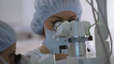 Doctors look through a microscope during surgery, microsurgery, NATURAL GRADE Stock Footage 51445836
