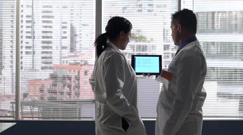 Doctors looking at medical chart on tablet wide shot Stock Footage 48030066