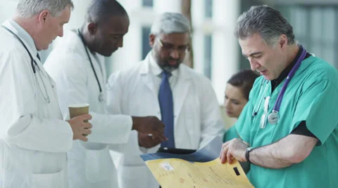 Doctors, nurses and surgeons in group meeting. A touch screen device is central Stock Footage 32963048