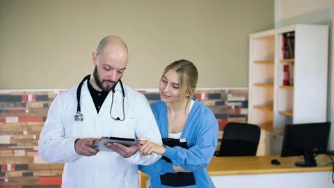 Doctors, nurses and surgeons in group meeting. A touch screen device is central Stock Footage 74284615