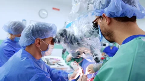 Doctors performing neurosurgery look at microscope. Stock Footage 309406560