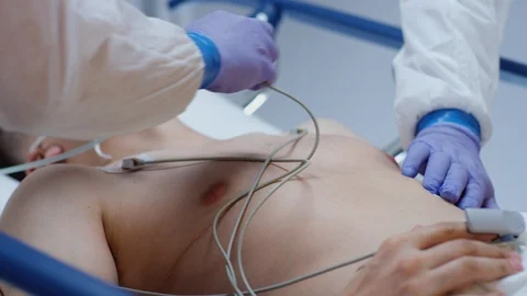 Doctors in Protective Suits Attaching ECG Leads to Coronavirus Patient Stock Footage 126525312
