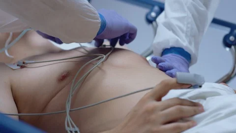 Doctors in Protective Suits Attaching ECG Leads to Coronavirus Patient Stock Footage 126526776