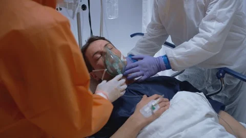 Doctors in Protective Suits Putting on Oxygen Mask on Coronavirus Patient Stock Footage 126519728