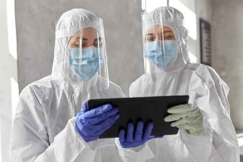 Doctors in protective wear with tablet computer Stock Photos