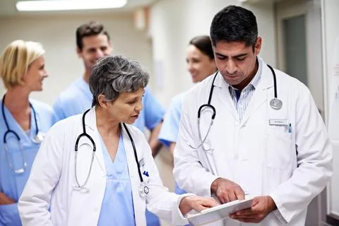 Doctors, reading and group with paperwork in hallway, help and health services Stock Photos