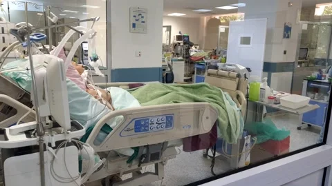 Doctors in reflection in ICU with patient in bed 스톡 동영상 145798139