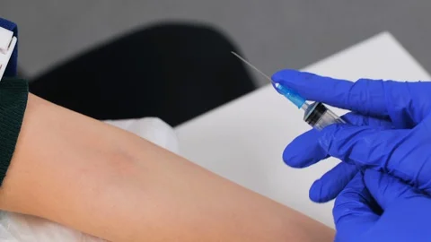 The doctor's several times trying to find a vein with a syringe. 動画素材 128371932