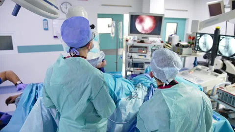 Doctors standing with their backs to the camera over the patient. Stock Footage 170096513
