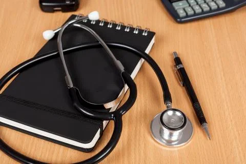 Doctors stethoscope laying on a notepad on a desk Stock Photos