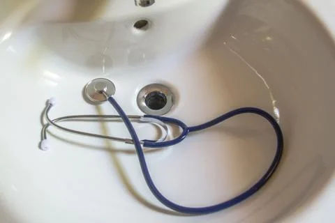 Doctors stethoscope resting on a white bathroom sink Stock Photos