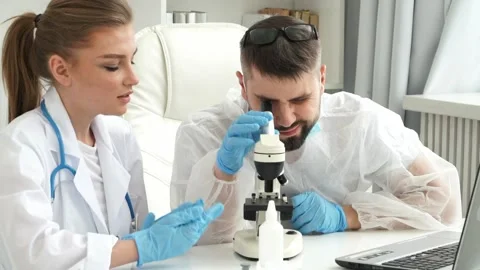 Doctors in suit and masks explore virus covid-19 under microscope in laboratory. Stock Footage 150084745