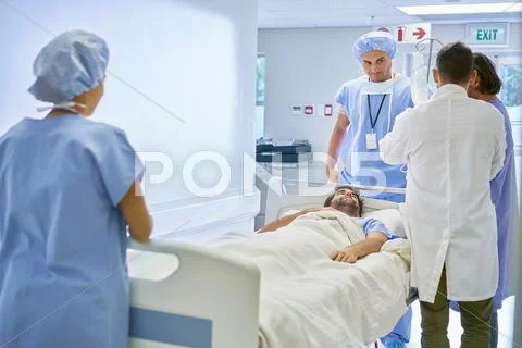 Doctors Surrounding Patient In Hospital Bed