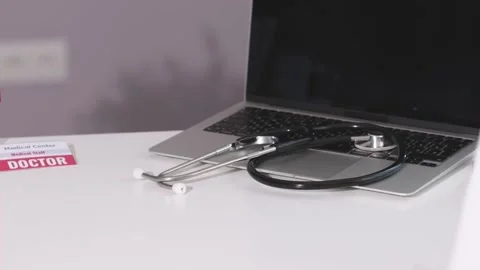 Doctor's table workplace clinical office table laptop stethoscope doctor badge Stock Footage 224174123