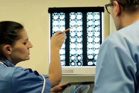 Doctors with tablet computer looking at x-ray scan of human brain NTSC Stock Footage 33702447