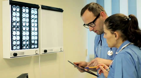 Doctors with tablet computer looking at x-ray scan of human brain Vídeos de archivo 33791444