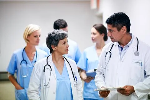 Doctors, talk and group with paperwork in hallway, help and healthcare services Stock Photos