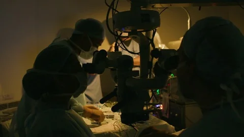 Doctor's team discussing in a semi-lit room with operating tools laid on a table Stock Footage 77447827