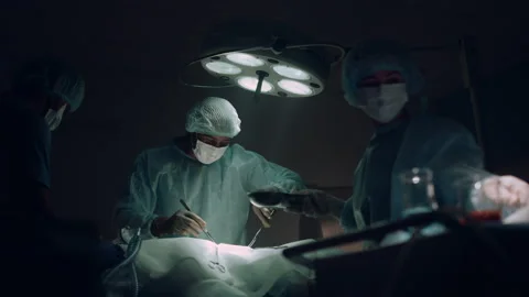 Doctors team performing surgical operation in dark hospital operating room. Stock Footage 179416401