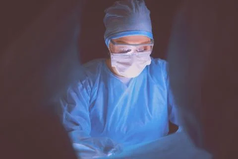 Doctors team in surgery in a dark background. Stock Photos