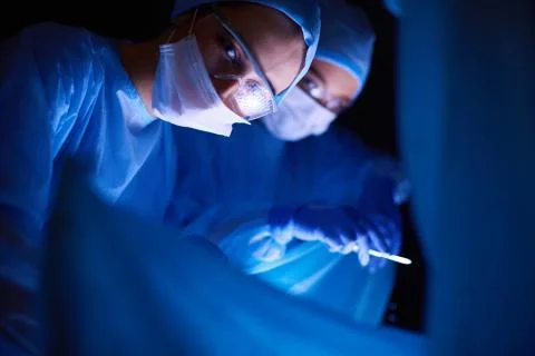 Doctors team in surgery in a dark background. Stock Photos