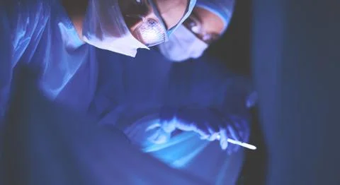 Doctors team in surgery in a dark background. Stock Photos